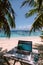 Laptop on wooden table with a serene beach scene in the background.