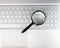 Laptops keyboard through magnifying glass. Internet search and keywording concept