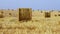 Large agricultural field dotted with golden bales of hay in the background. 4K