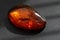 Large amber stone illuminated by sunlight on a black background close-up