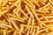 Large amount of golden-brown French fries sticks randomly arranged