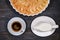 Large apple pie and cup coffee and creamer. Fruit cakes in a baking dish. Homemade pie of ripe apples on a wooden dark background