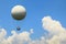 A large balloon in the blue sky above the clouds