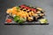 Large beautiful set of different types of sushi maki and nigiri on a black rectangular stone slate plate.