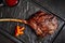 Large beef tomahawk steak with sauce at black stone background garnished with french fries