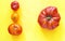 A large big natural tomato and 3 small ones on a yellow orange background. One is more than three. No waste. Save the