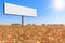 Large billboard on a cornfield on background of a blue sky and bright sun