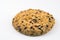 A large biscuit strewn with sesame seeds and nuts on a light background