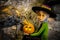 Large black crow with crown looms over cute witch with pumpkin in Halloween decor secenaio-blurred background