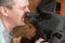 A large black dog licks a man`s face. Adult female Rottweiler dog kissing the owner. An adult male with his eyes closed with