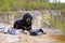 A large black dog of the Tibetan Mastiff breed on a picnic lies on a blanket and looks to the side.