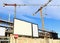 Large blank information boards  in front of the new building under construction. Crane towers above.