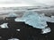 Large blue ice icebergs washed onto a black sandy beach in Iceland.