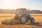 Large blue tractor plow plowed land after harvesting the maize crop on a sunny, clear, autumn day.