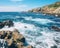 large body of water with a cliff in the distance waves slamming the rocks.