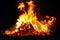 Large bonfire, burning and glowing with soft flames, sparkles flying agains the dark sky. Glowing wood silhouette. Walpurgis night