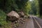 large boulders and mud covering road after landslide