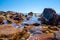 Large boulders with seashells in shallow ocean bay water.