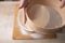 Large bowl, cutting board, sieve for sifting flour on the table. Female hands sifting flour in the home kitchen