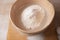 Large bowl, cutting board, sieve for sifting flour on the table. Female hands sifting flour in the home kitchen