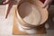 Large bowl, cutting board, sieve for sifting flour on the table. Female hands sifting flour in the home kitchen