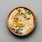 Large bowl of homemade hummus garnished with chickpeas, red sweet pepper, parsley and olive oil