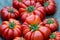 Large, bright red beef tomatoes sit in a large wooden bowl