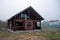 Large brown unfinished wooden house in dry grass