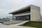 A large building with sleek lines and a glass facade, featuring steps leading up to the entrance, A modern museum with sleek lines