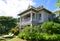 A large bungalow resort with sundeck chairs in front surrounded by green trees and plants