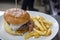 Large burger with egg and salad, and a big portion of fried chips aside set on a plate ready to be served