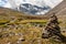 A large cairn in the foreground of a mountain landscape.