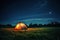 A large camping tent is lit up in a meadow at night