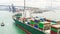 Large cargo ship transporting shipment container arriving Hong Kong port, bridge and city background, drone aerial view