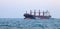large carrier ship floating afternoon in sea, tugboat dragging container ship, blue sky evening background and sea front, mode of