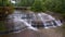 Large cascading waterfalls into river with bridge in background