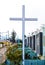 A large Catholic cross, stands among the houses on the street.