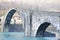 Large central arch of the Maddalena bridge built in stone under a fog cushion called the devil`s bridge on a cold winter morning.