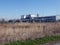 Large chemical plant behind field and heavy foliage