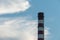 A large chimney against the sky and clouds. Environmental pollution. Emission of harmful substances into the atmosphere.