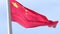 Large Chinese national state flag waving in the wind on a flagpole against a blue sky close up