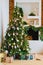 a large Christmas tree with boxes of gifts by the decorative fireplace