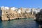 large cliff on the seashore, buildings built on the rocks right on the seashore, Polignano a Mare, people bathing in the sea