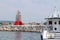 A large coast guard boat stands in a marina near a breakwater with a red lighthouse. Police ship at the entrance to the seaport.