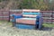 A large colored and dirty chair of wooden boards stands in the sand in the street