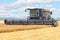 A large combine harvester harvesting wheat on a summer day