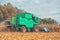 A large combine harvester harvests corn on the field on a sunny day