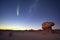 large comet passing over a desolate desert terrain at night