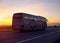 A large comfortable passenger bus against the orange sky with sunset rides on the highway. The concept of European passenger