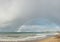 large complete full half circle rainbow stretching across the sky into the ocean at Apollo Bay, Victoria, Australia